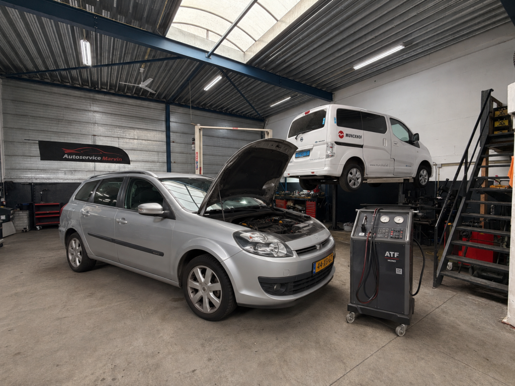Auto met geopende motorkap en spoelapparaat in de werkplaats van